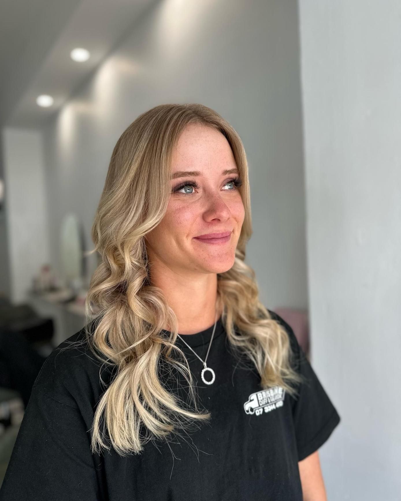 A Woman with Blonde Hair Is Wearing a Black Shirt and A Necklace  — Losh Hair Lounge In Toowoomba City, QLD
