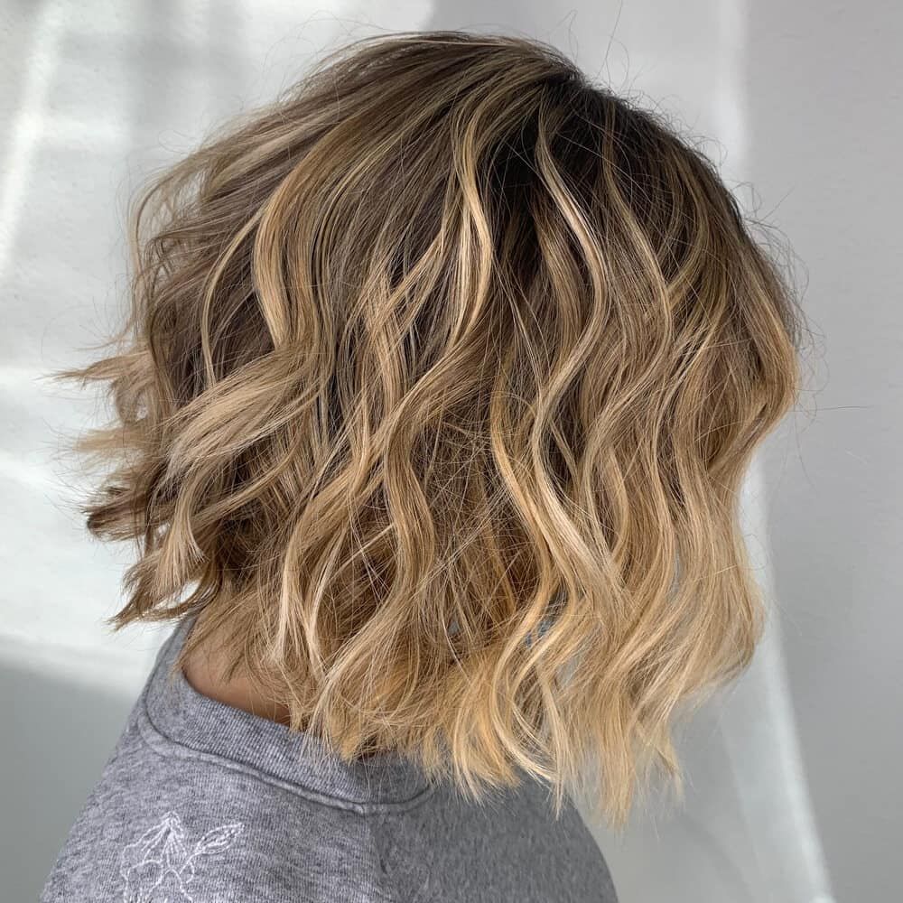 A Woman With Short Wavy Blonde Hair is Wearing a Grey Sweater — Losh Hair Lounge In Toowoomba City, QLD