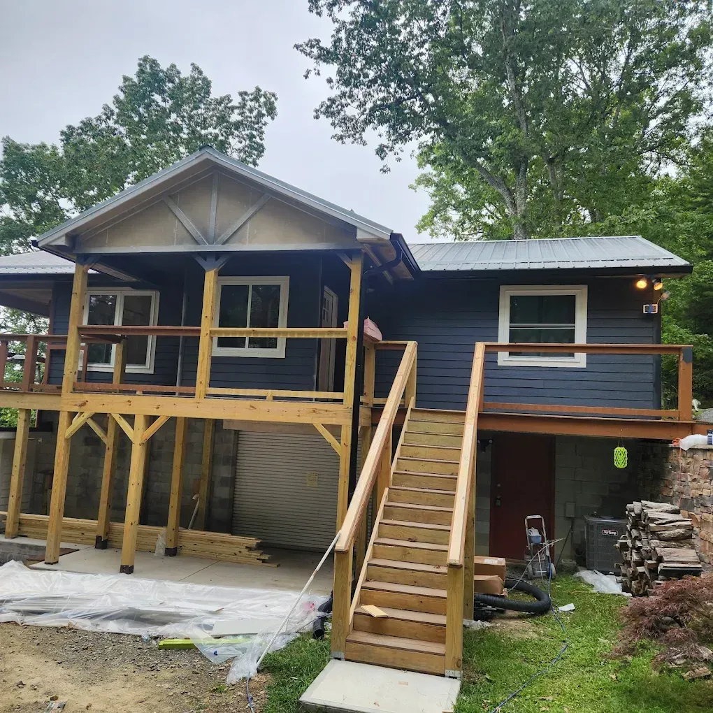 Blue house under renovation with wooden porch, stairs, and two-story deck under construction