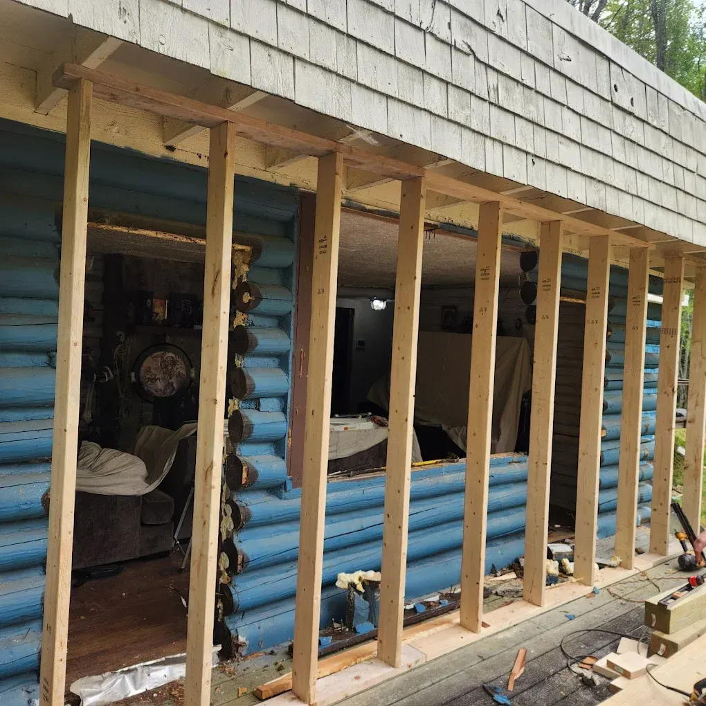 House exterior under renovation with exposed blue insulation and vertical wooden framing studs