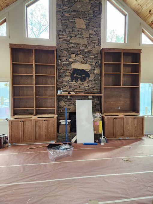 Fireplace wall with built-in wood shelves in an unfinished room, with tools and materials on the floor