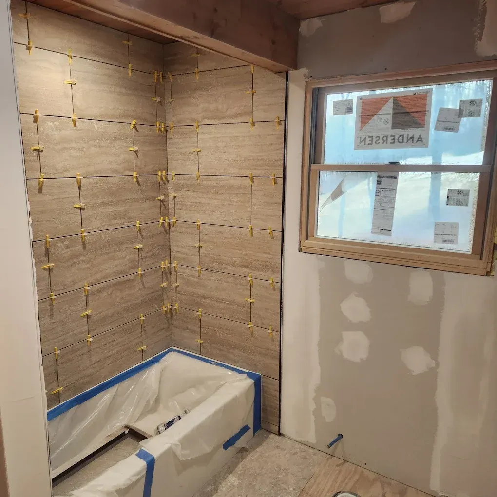 Bathroom under renovation with insulated walls, a covered tub, and a window.