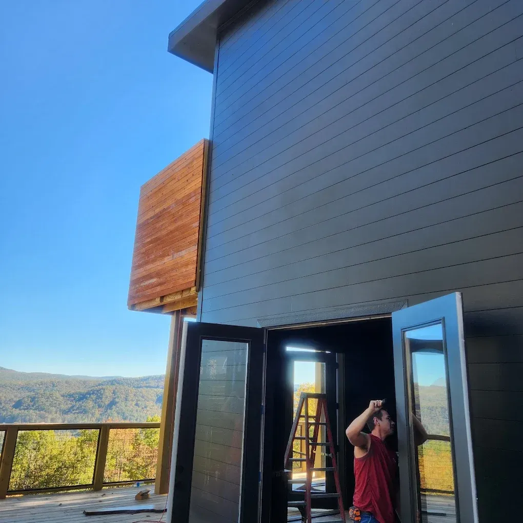 Open patio door on a modern house with a person standing outside under a blue sky