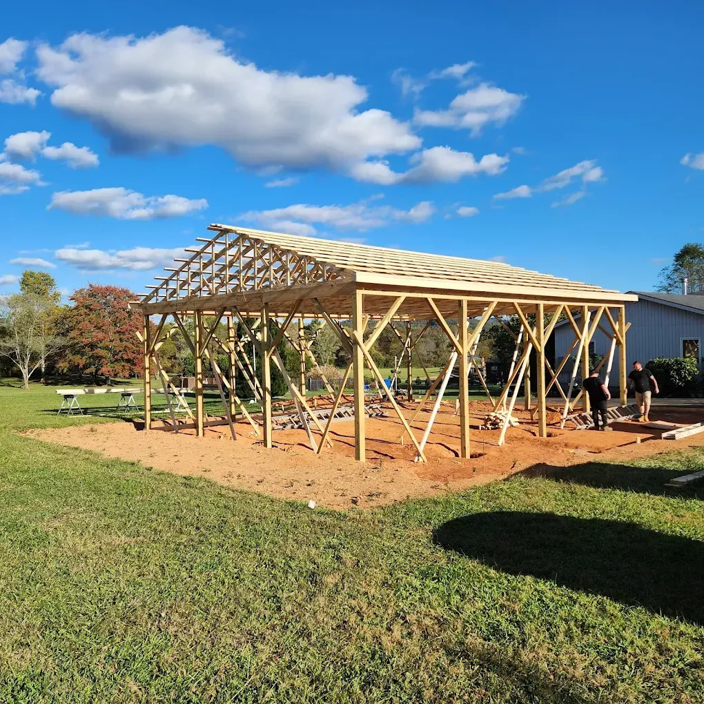 Partially built wooden shed frame on a grassy lot under a blue sky with clouds