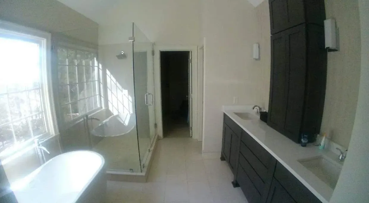 Modern bathroom with bathtub, shower, large mirror, and dark vanity cabinets