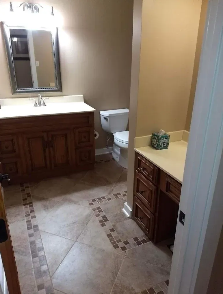 Bathroom with wood vanity, large mirror, toilet, and beige tile floor.