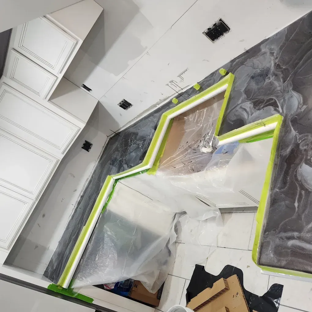 Room under renovation with plastic sheeting, green painter’s tape, and exposed ceiling panels