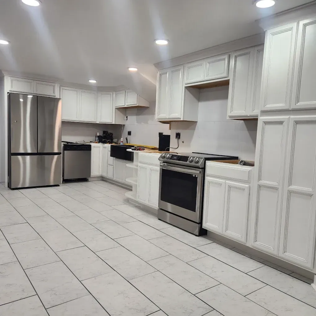 Bright white kitchen with stainless steel appliances, tile floor, and recessed lighting
