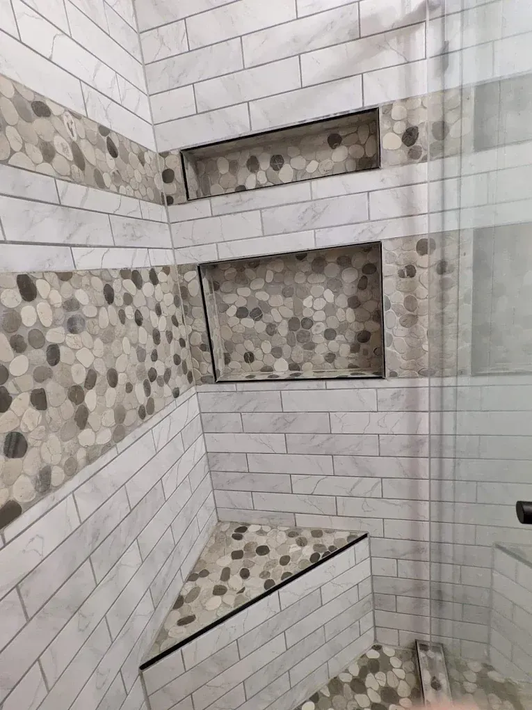 Tiled bathroom shower wall with built-in shelves and hexagon mosaic accents