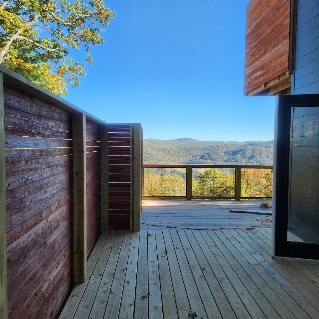 Wooden deck with mountain view through an open glass door on a sunny day