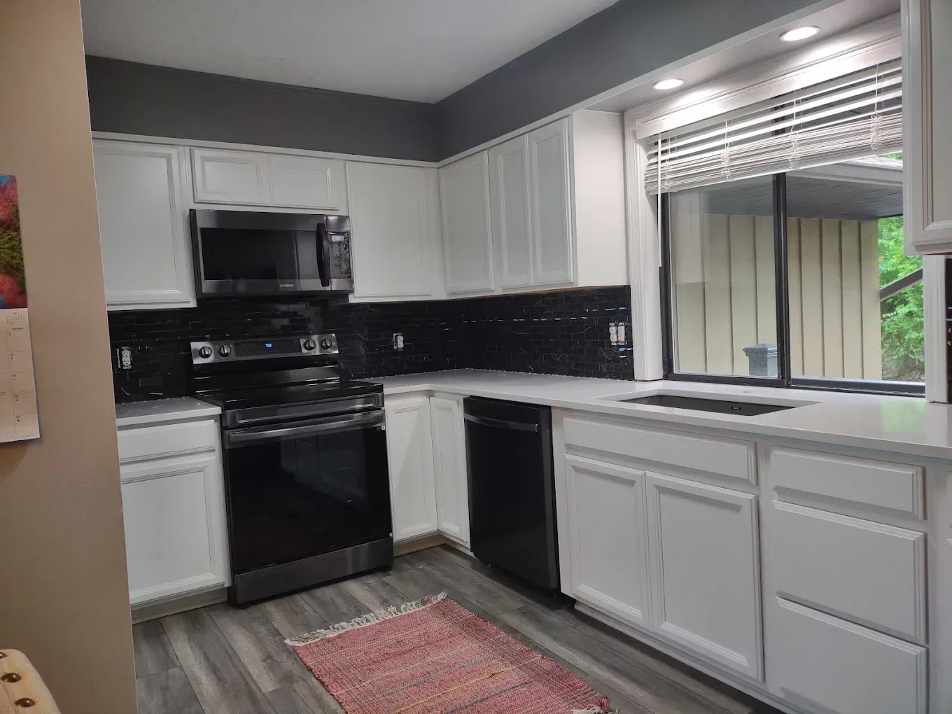 Modern kitchen with white cabinets, black appliances, and a window over the sink