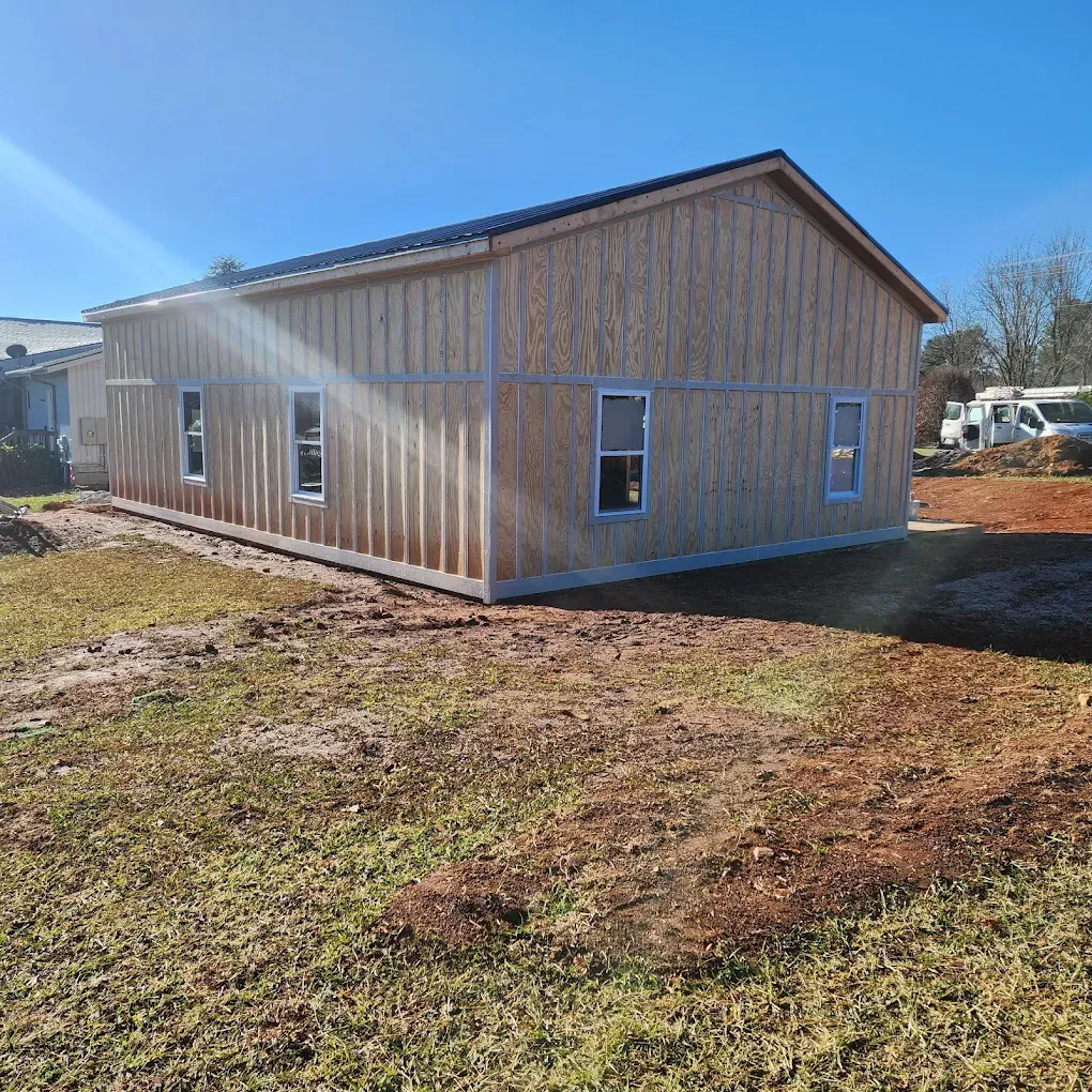 New wooden house exterior under construction on a sunny day, with siding and windows installed