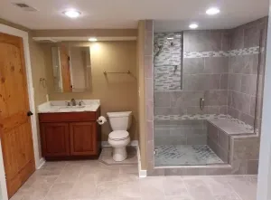 Bathroom with sink, toilet, and tiled walk-in shower with bench