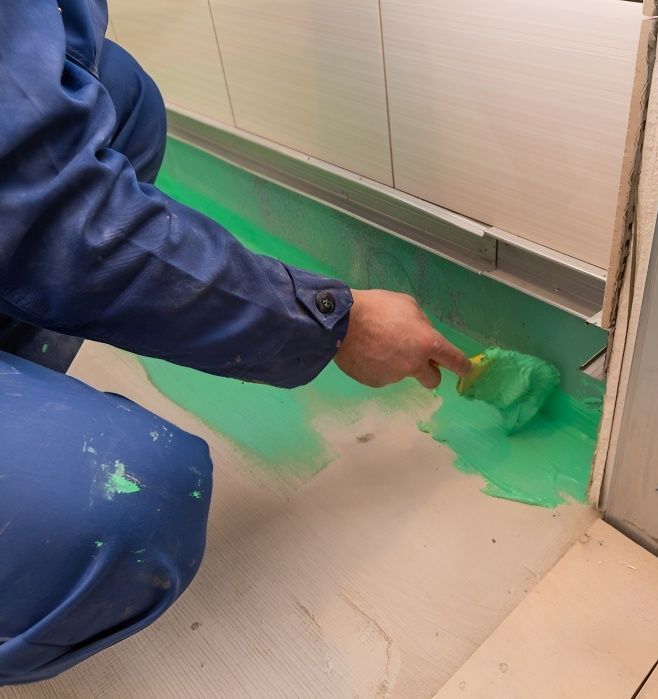 A Person is Kneeling Down and Painting the Floor With a Brush  — Mick's Carpentry & Maintenance In Machans Beach, QLD