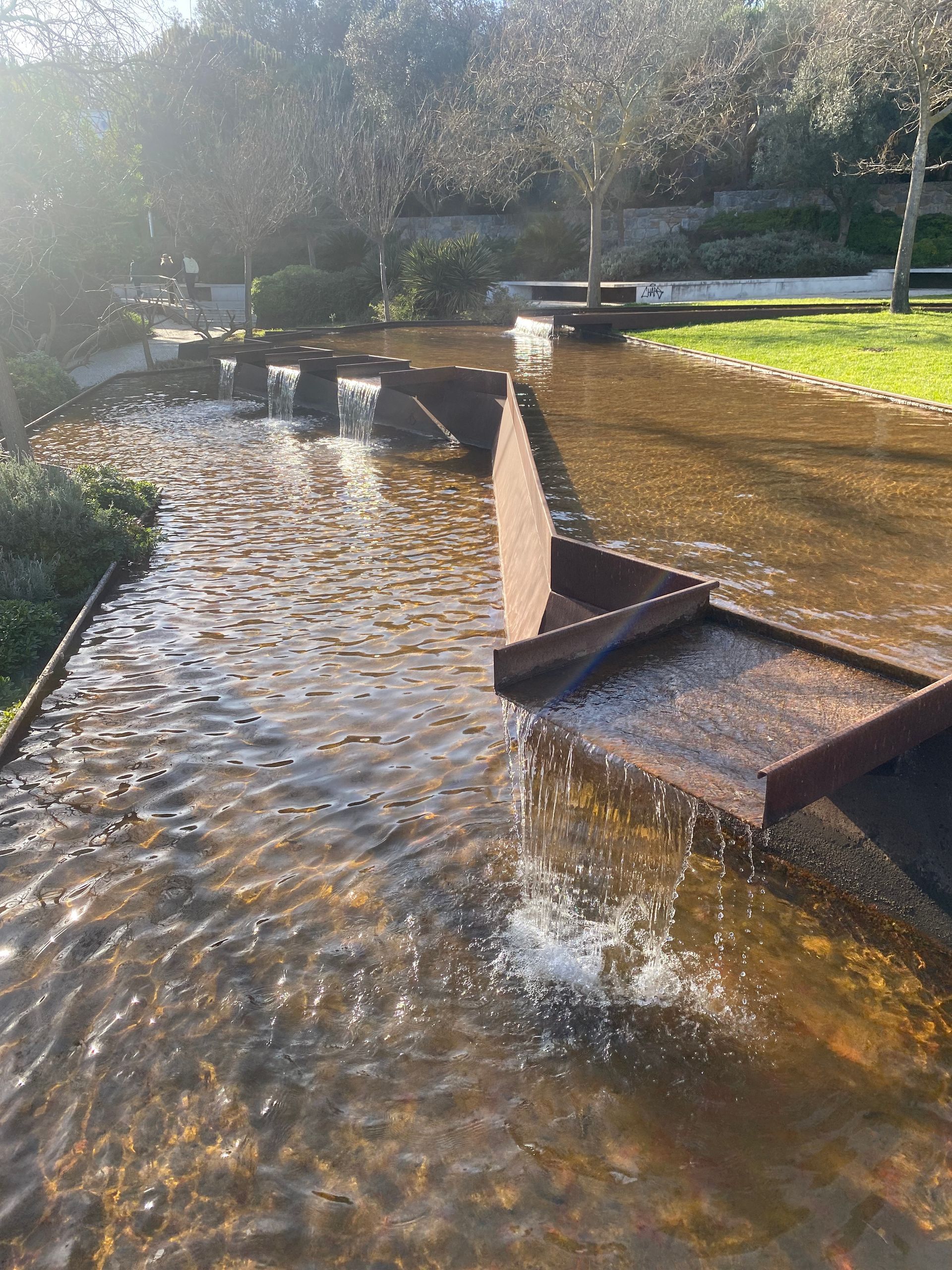 une petite fontaine dans un parc avec de l' eau qui coule dessus .