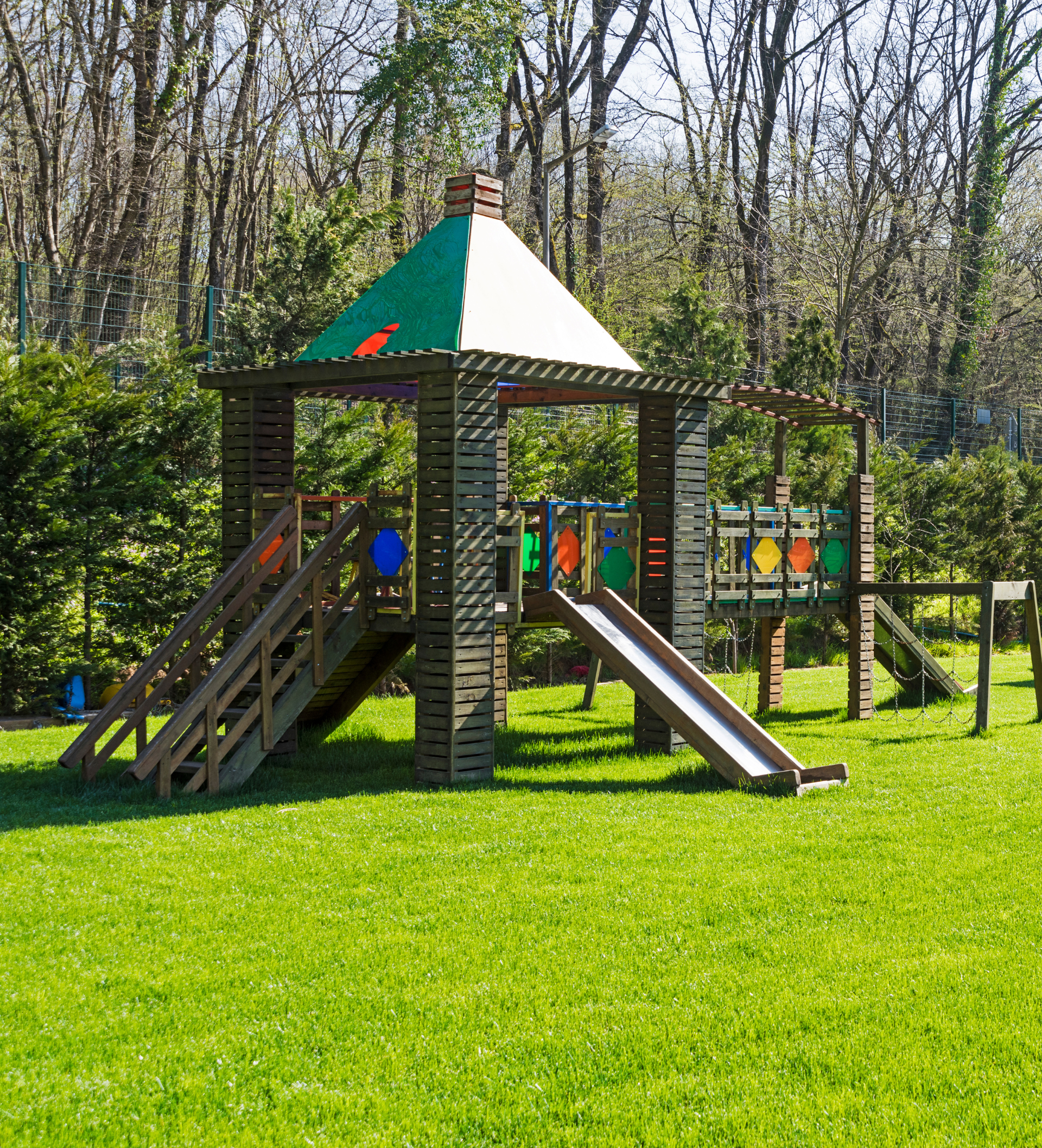 une aire de jeux avec un toboggan et un gazebo en bois