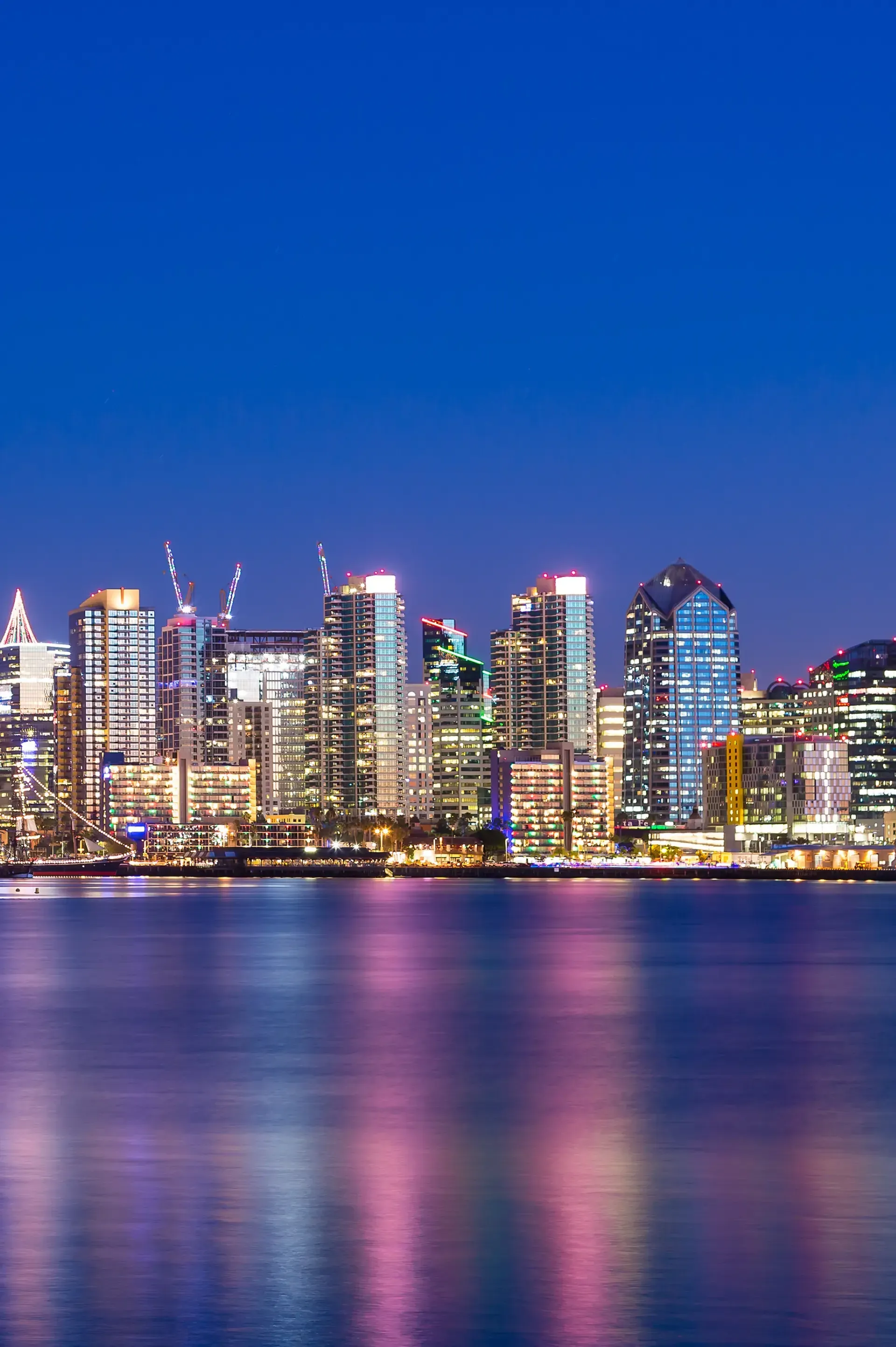 HWH San Diego Hard Money Lender - Real Estate captures the vibrant city of San Diego at night, with tall buildings glowing under bright city lights.