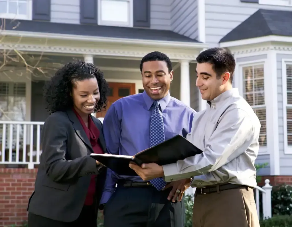 San Diego Hard Money Lender - The image features three professionals reviewing documents in front of a house, highlighting seamless financing solutions.