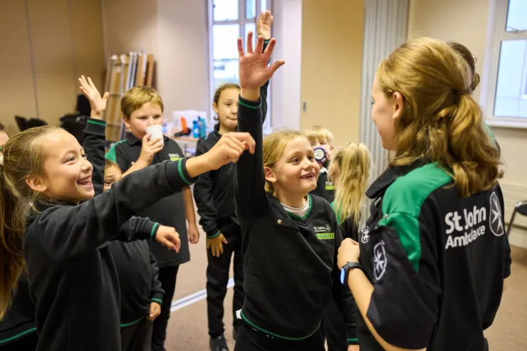 Children in black sportswear high-five a coach in a gym room