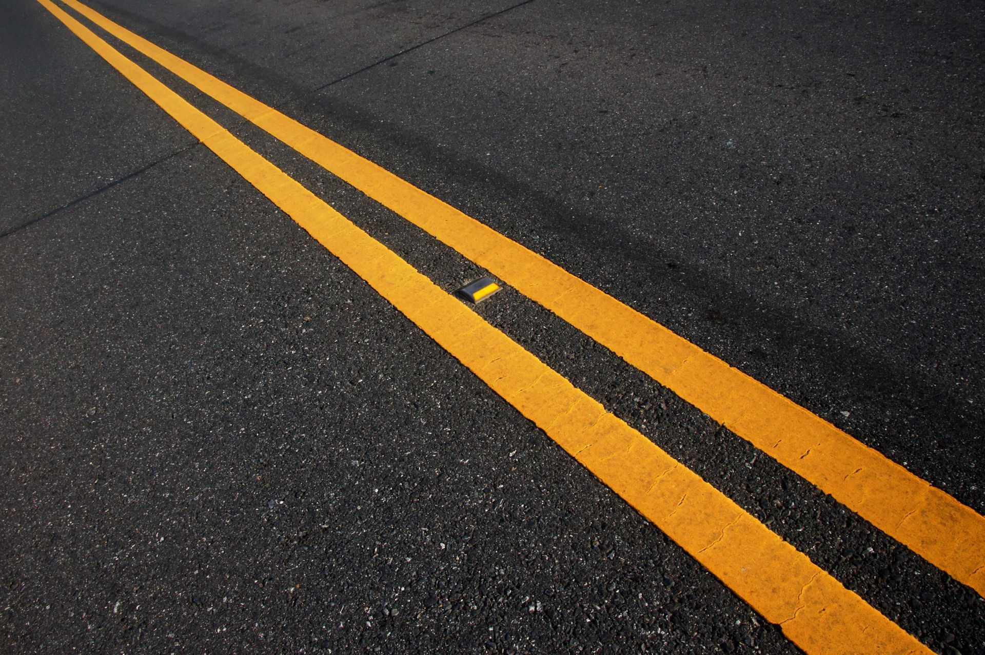 Yellow double lines on dark asphalt road, close-up view