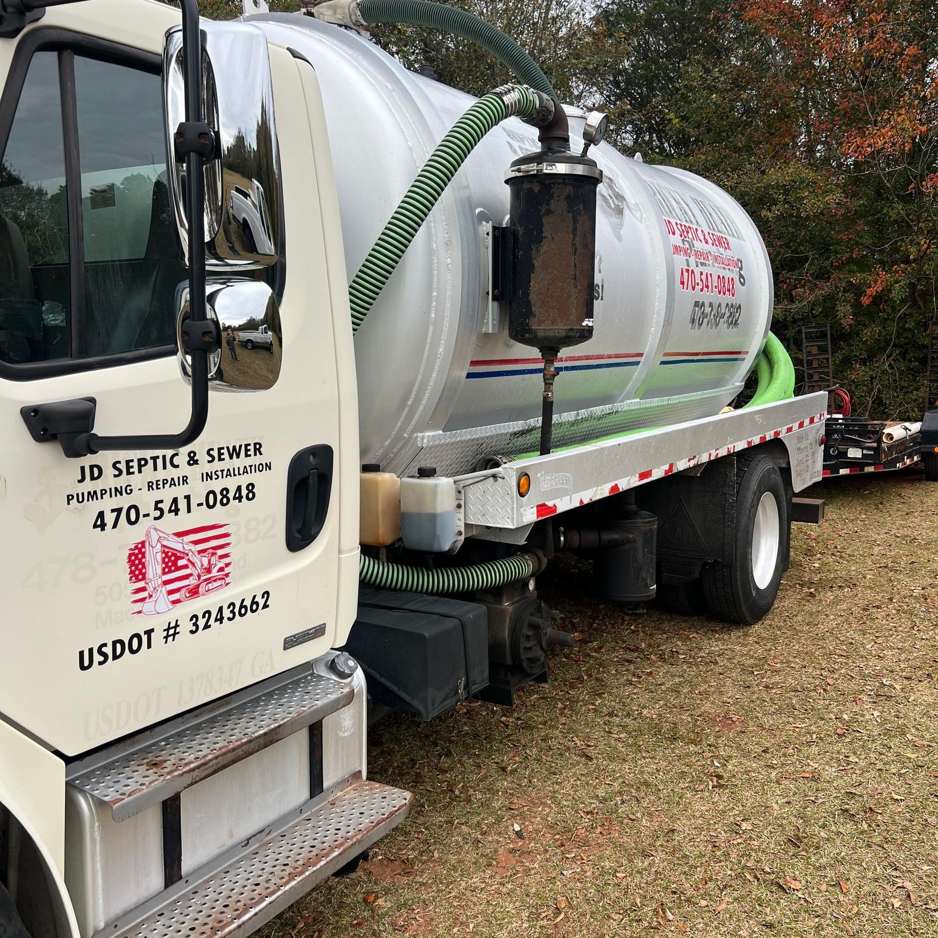 Septic tank truck, silver tank, JD Septic & Sewer logo, parked outdoors on grass.