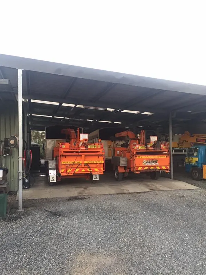 A Row of Orange Trucks Are Parked Under a Covered Area — Ability Tree Service in Darawank, NSW