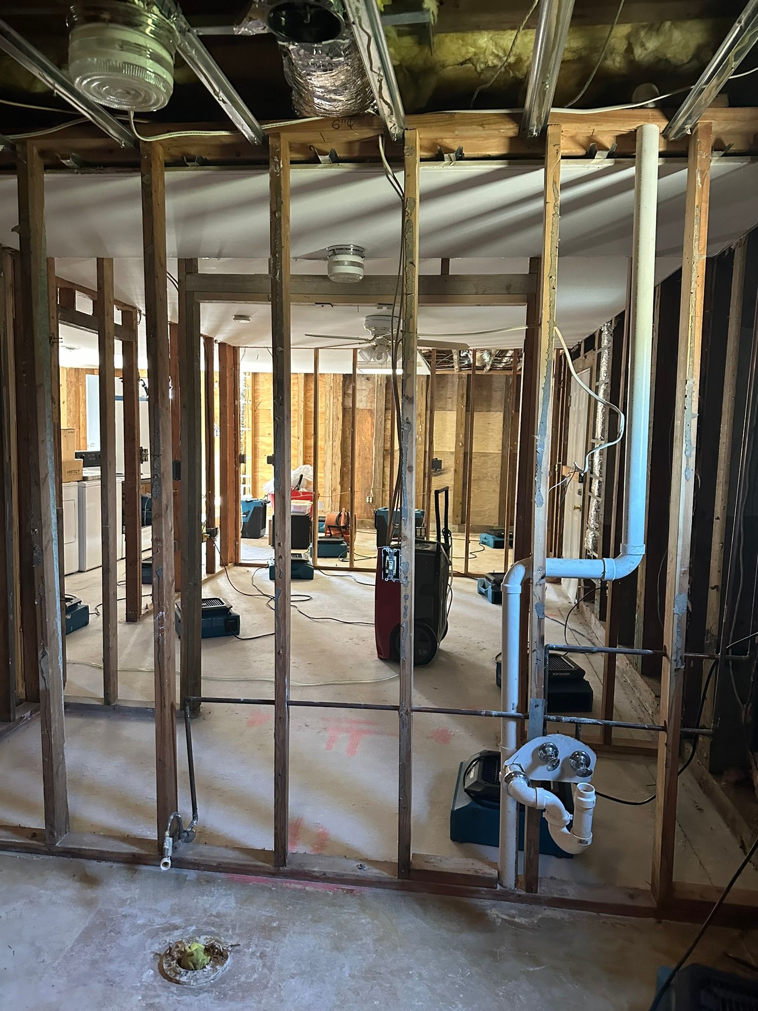 Interior of a house under renovation, with exposed wall studs, wiring, and construction debris.