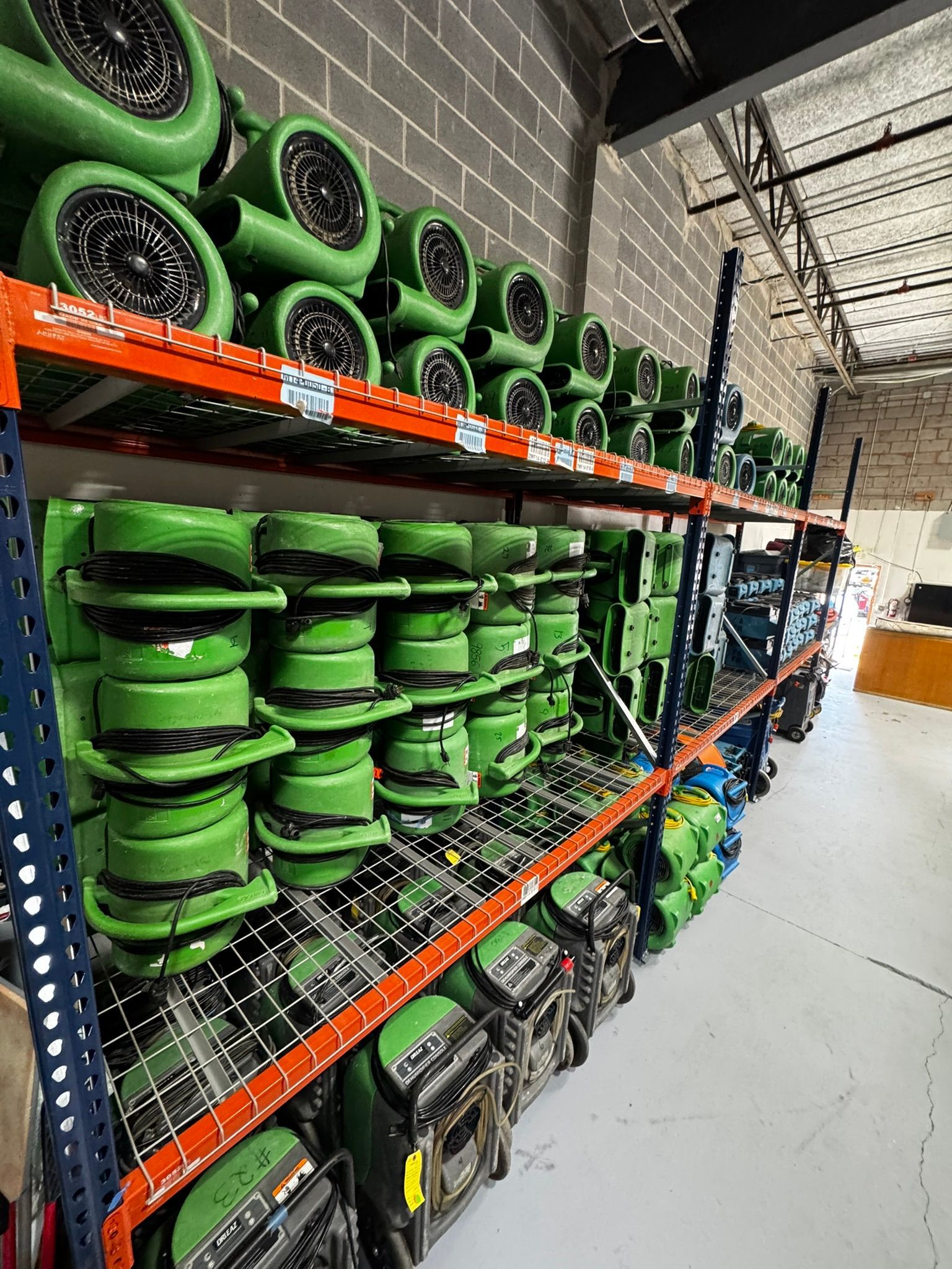 Green wheel rims and tires stacked on store shelves in a warehouse aisle