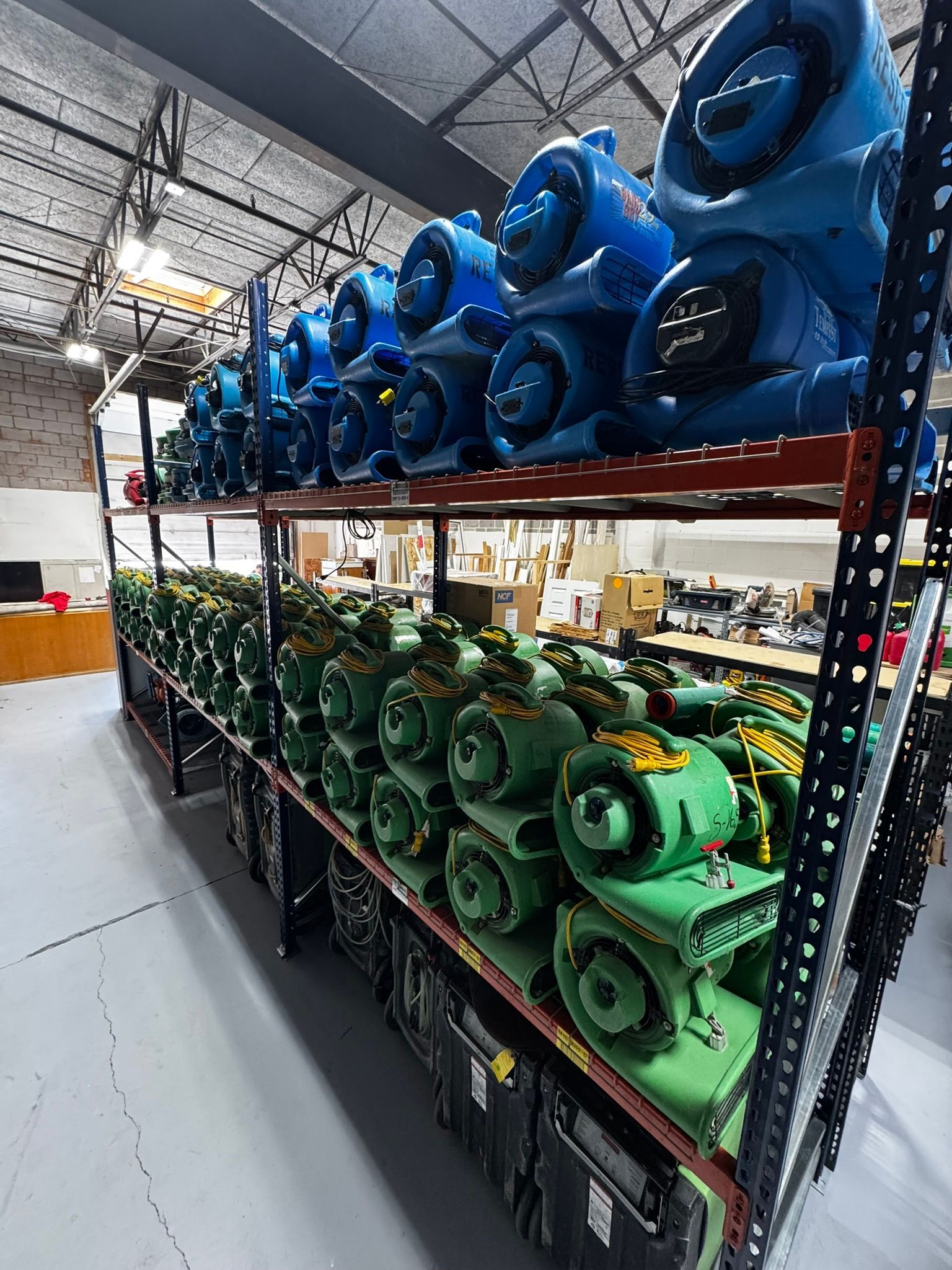 Warehouse shelves stacked with blue and green industrial blowers or motors