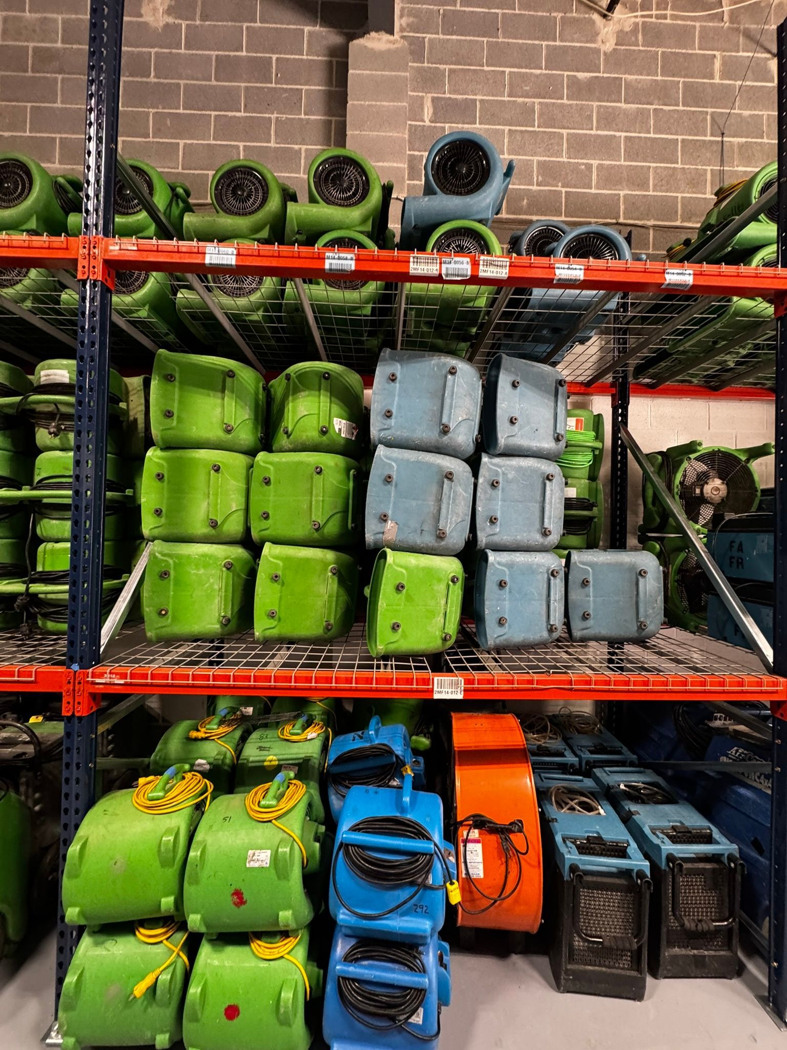 Rows of colorful outdoor gear bags and rolled mats stacked on metal shelves in a store.