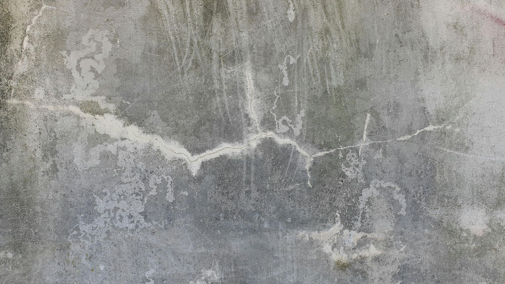 Close-up of a gray concrete wall with a white horizontal crack or stain.