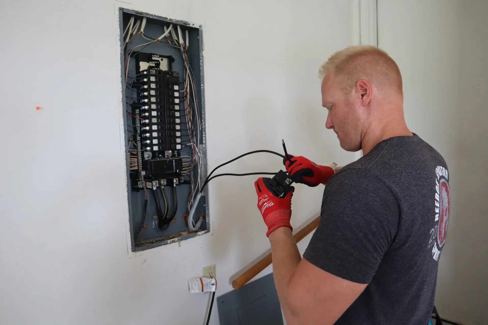 A man is working on an electrical panel on a wall.