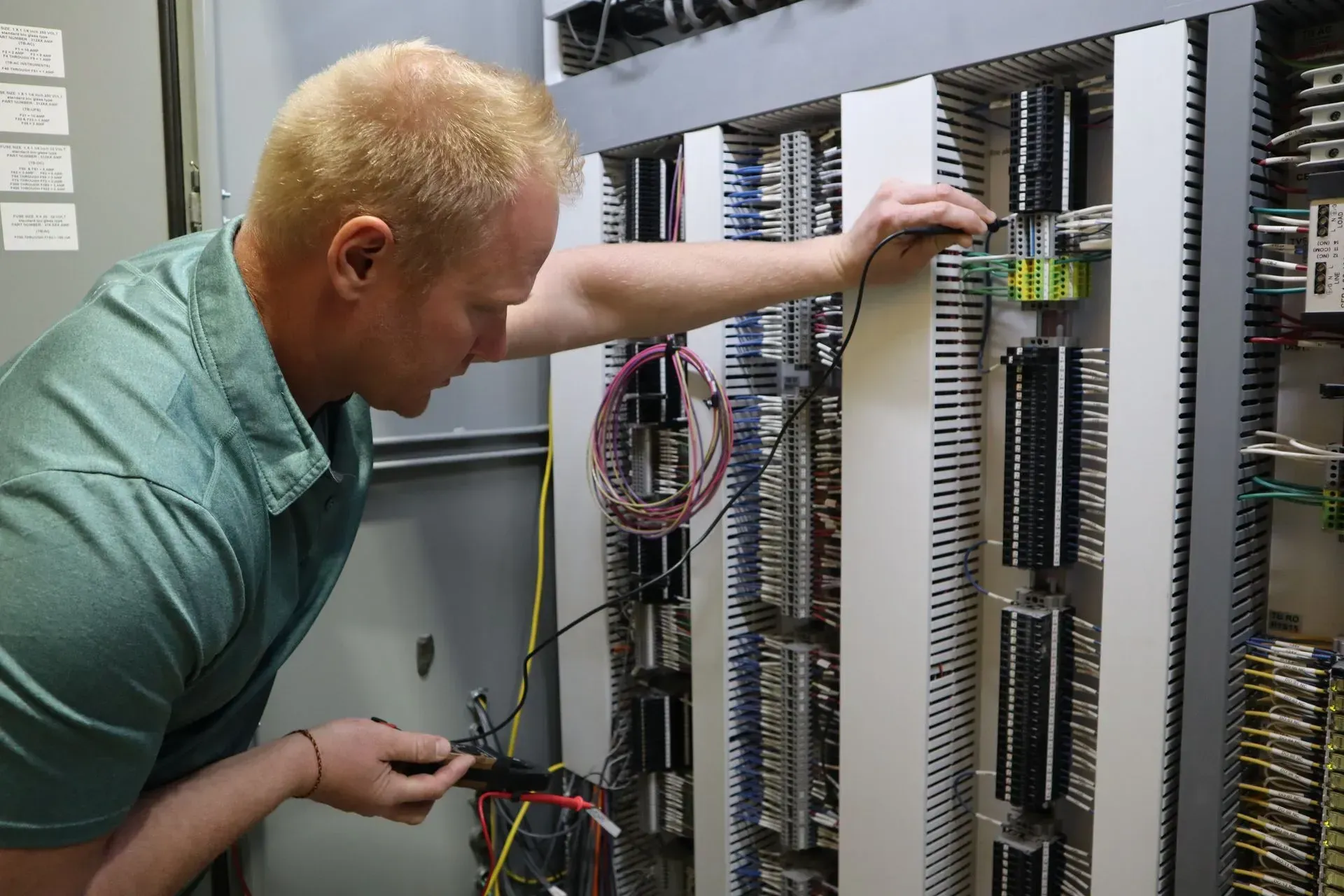 A man is working on a electrical panel with a screwdriver.