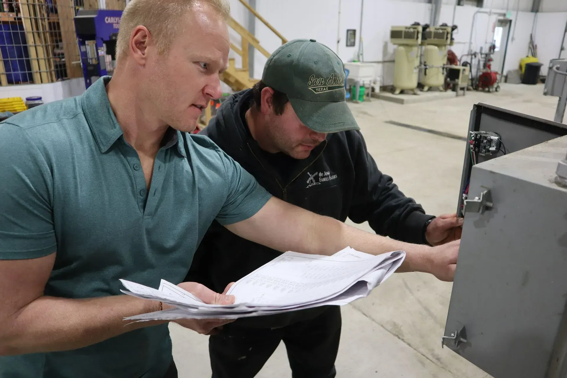 Two men are looking at a piece of paper in a factory.