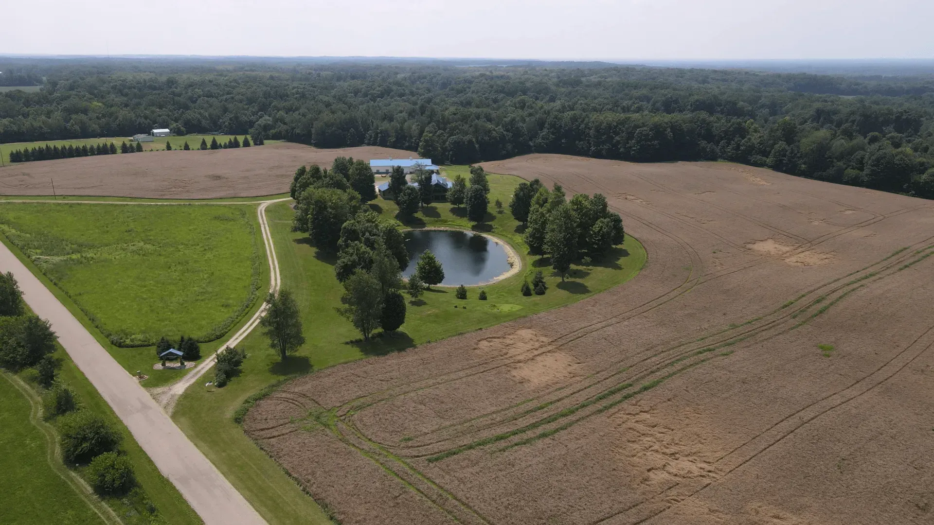 An aerial view of a farm with a pond in the middle of it.