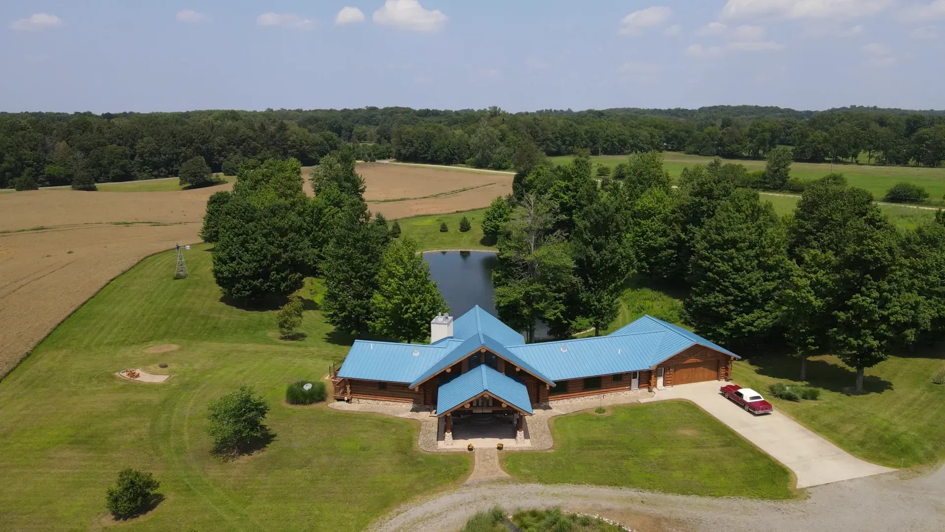 An aerial view of a house with a blue roof in the middle of a field.