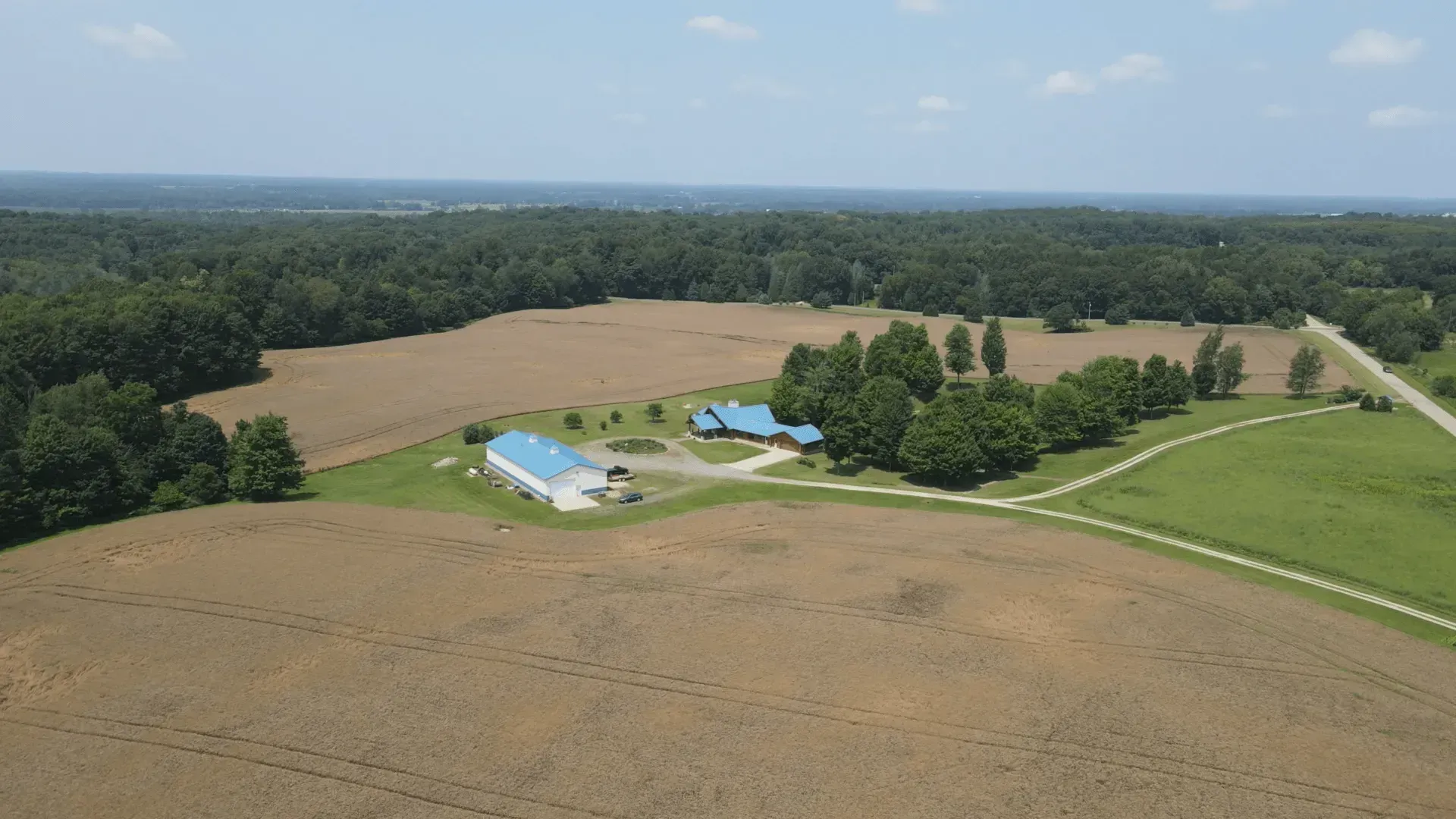An aerial view of a farm with a blue building in the middle of a field.