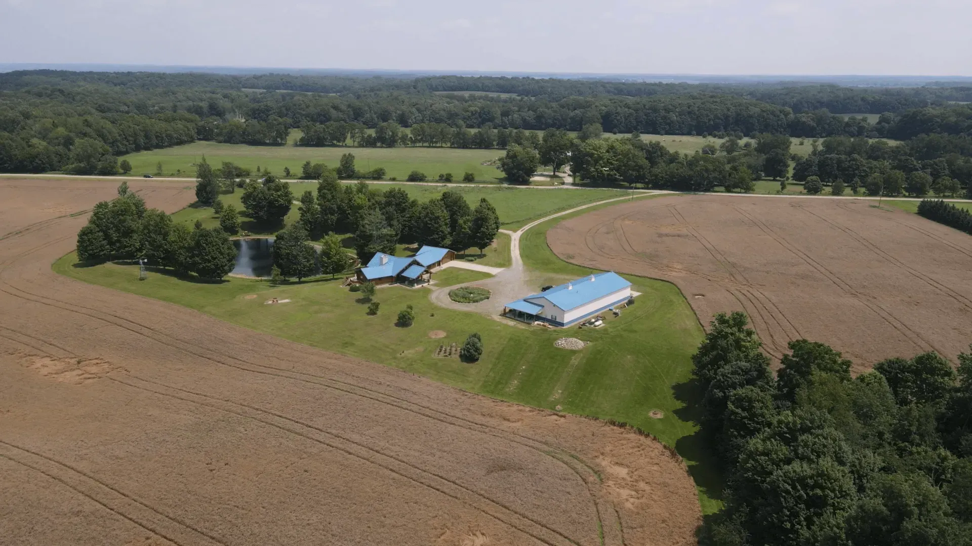 An aerial view of a farm with a blue building in the middle of a field.