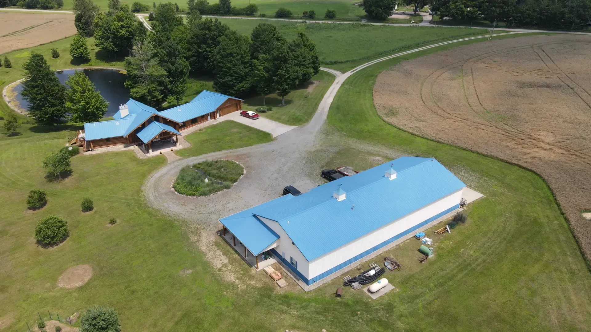 An aerial view of a large blue and white building in the middle of a field.