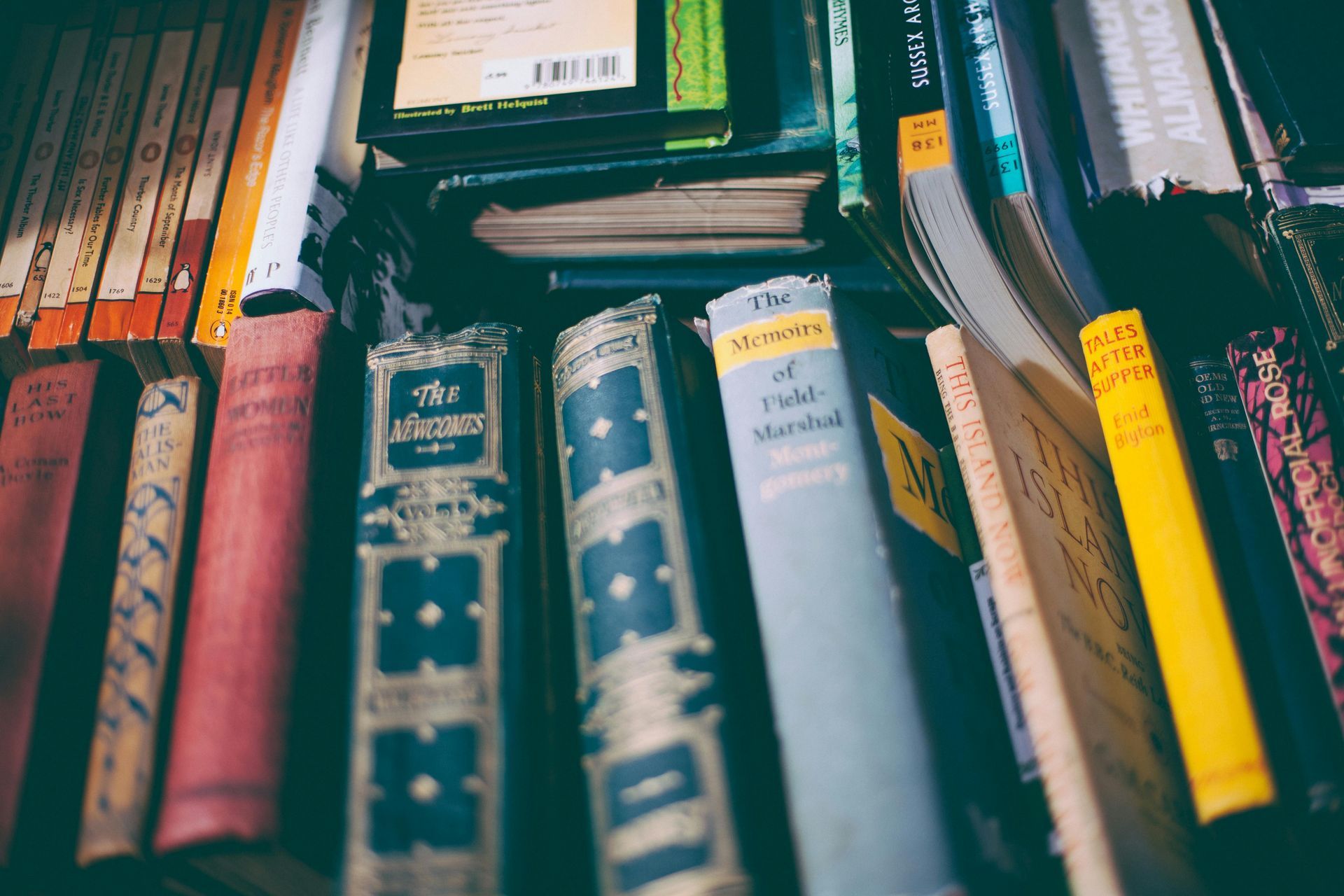A bunch of books are stacked on top of each other on a shelf.