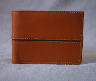 Cartera de cuero marrón sobre una superficie gris, cerrada y centrada sobre un fondo liso.