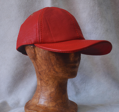 Gorra de béisbol roja sobre la cabeza de un maniquí de madera sobre un fondo gris.