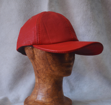 Gorro de cuero marrón sobre una cabeza de madera, mostrado sobre un fondo gris.