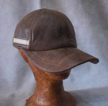Gorro de cuero marrón sobre una cabeza de madera, mostrado sobre un fondo gris.