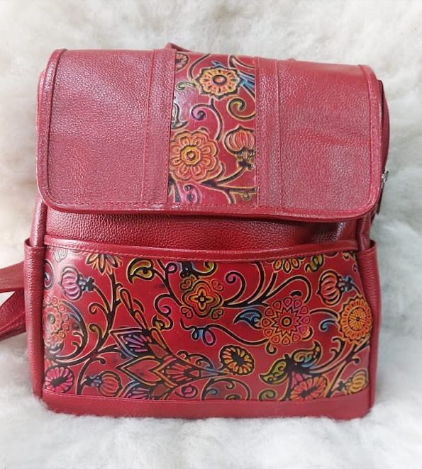 Mochila rosa con estampado floral, solapa superior y panel frontal colorido.