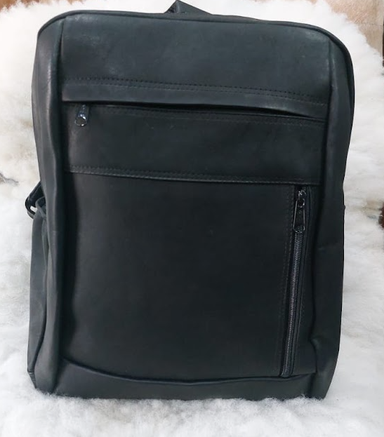 Mochila de piel negra con bolsillos delanteros con cremallera sobre una superficie blanca.