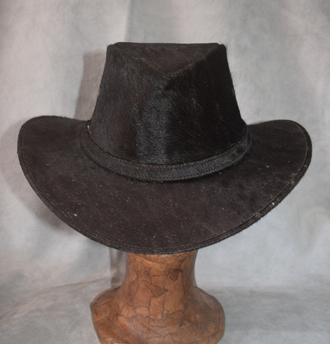 Sombrero de vaquero blanco sobre un soporte de madera sobre un fondo gris.
