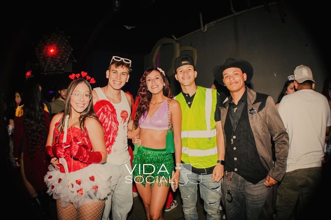 Five people in colorful costumes posing at a nighttime outdoor event.