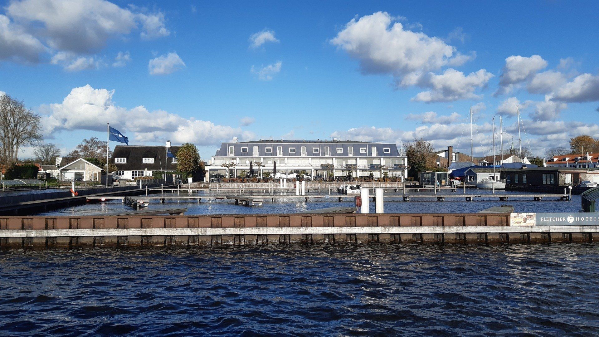 Een tafereel aan het water met een wit gebouw, een blauwe lucht en water.