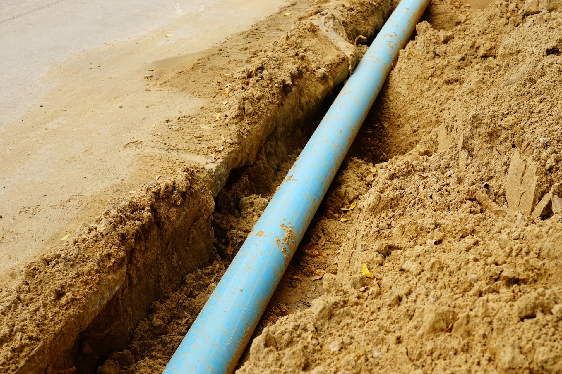 A blue pipe is laying in the dirt.